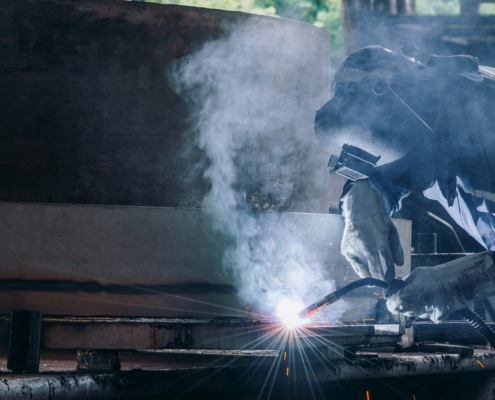 Worker using MIG welder on metal