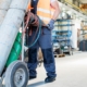 Low section of young manual worker moving gas cylinders in metal industry