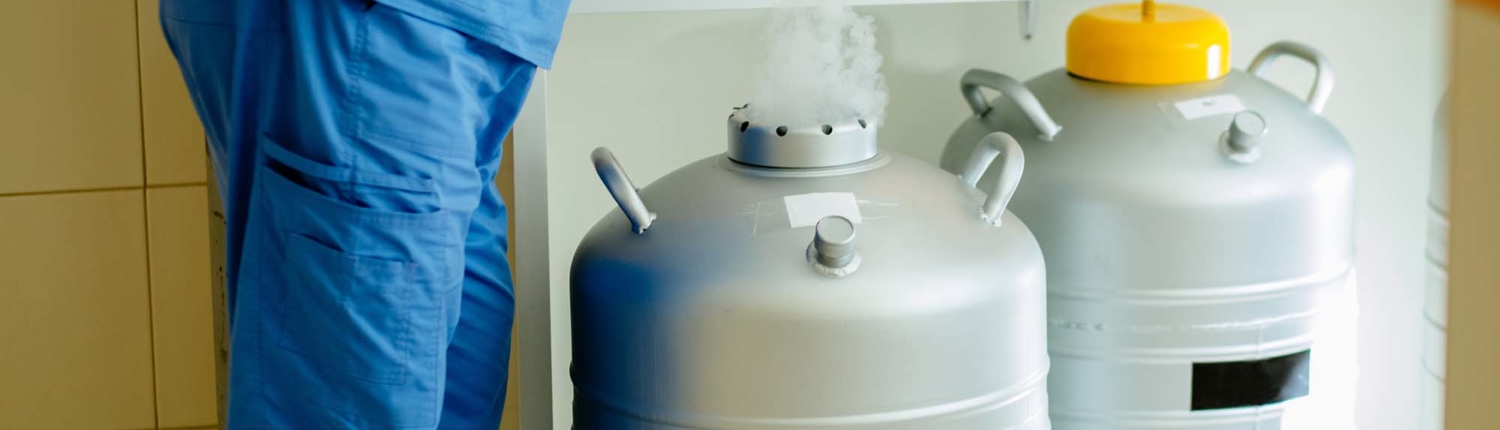 a worker wearing blue apparel is holding the top portion of a gas container