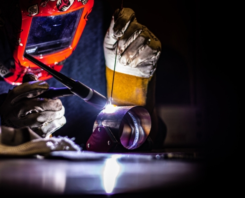 Worker using tig welder on meta pipe pieces