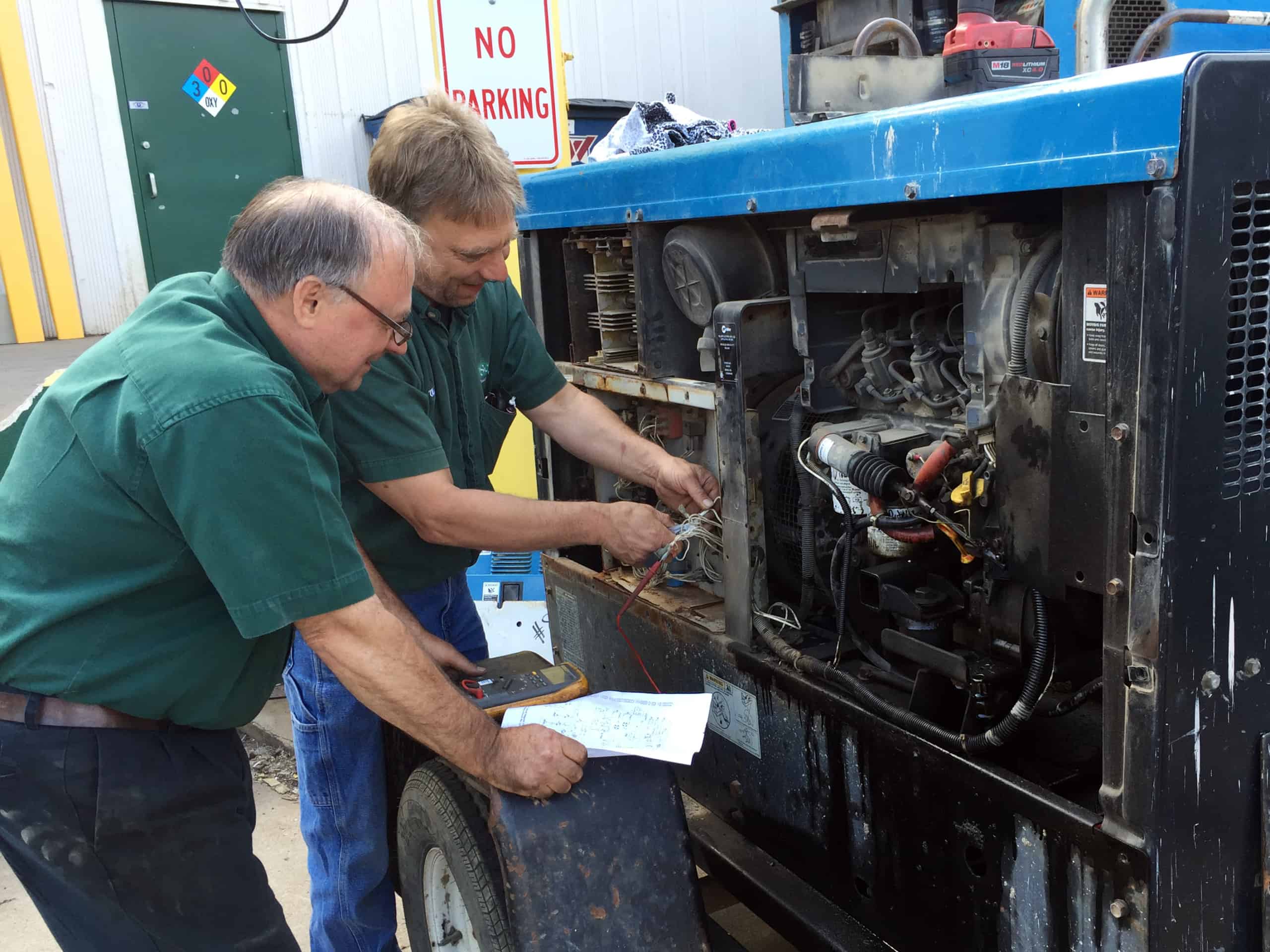 two OSC team members working on a machine together