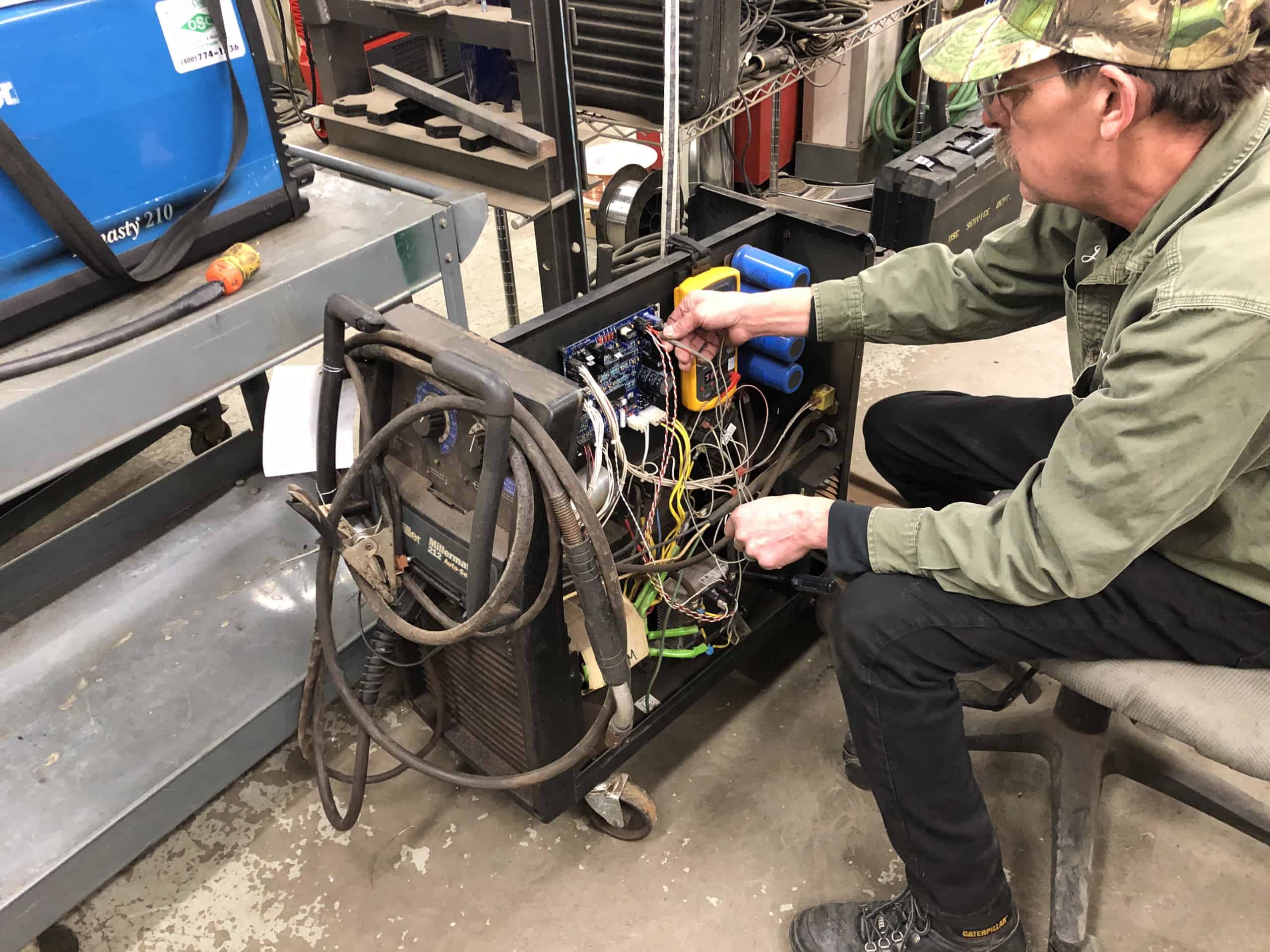 close up of OSC team member working on wires in a machine