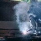 Worker using MIG welder on metal
