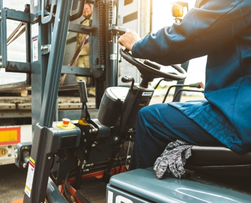A man on a forklift works in a large warehouse, unloads bags of raw materials