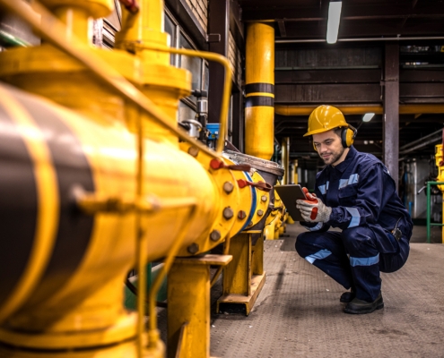 Industrial technician checking gas pipeline installations inside refinery