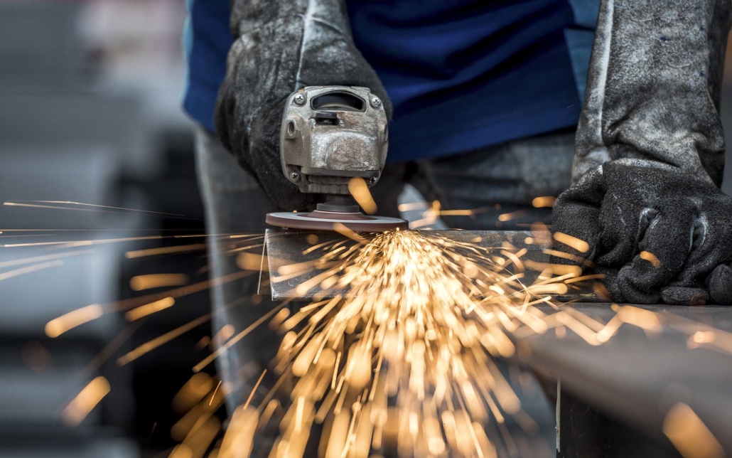 View of a worker using grinder to sand down metal