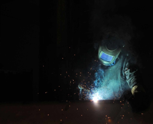 an electric welder welds metal structures at a factory